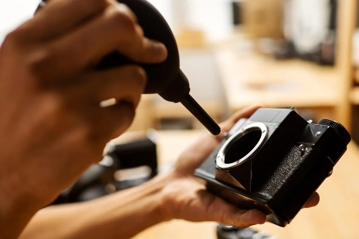 In Seitenansicht reparieren Hände eine Fotokamera.